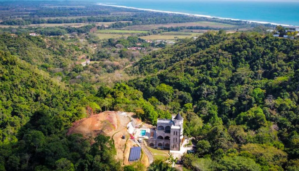 An Aerial photo of The Castle of Oz that shows the property, the jungle and the ocean.